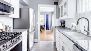 Una cocina moderna con armarios blancos, una estufa de acero inoxidable y una encimera de granito.