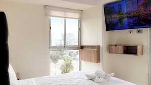 Ein Hotelzimmer mit Bett, Wandfernseher und Fenster mit Stadtblick.