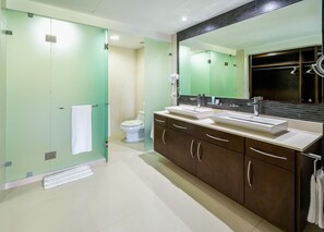 A modern bathroom with a glass shower enclosure, a toilet, and a vanity with dual sinks and a large mirror.