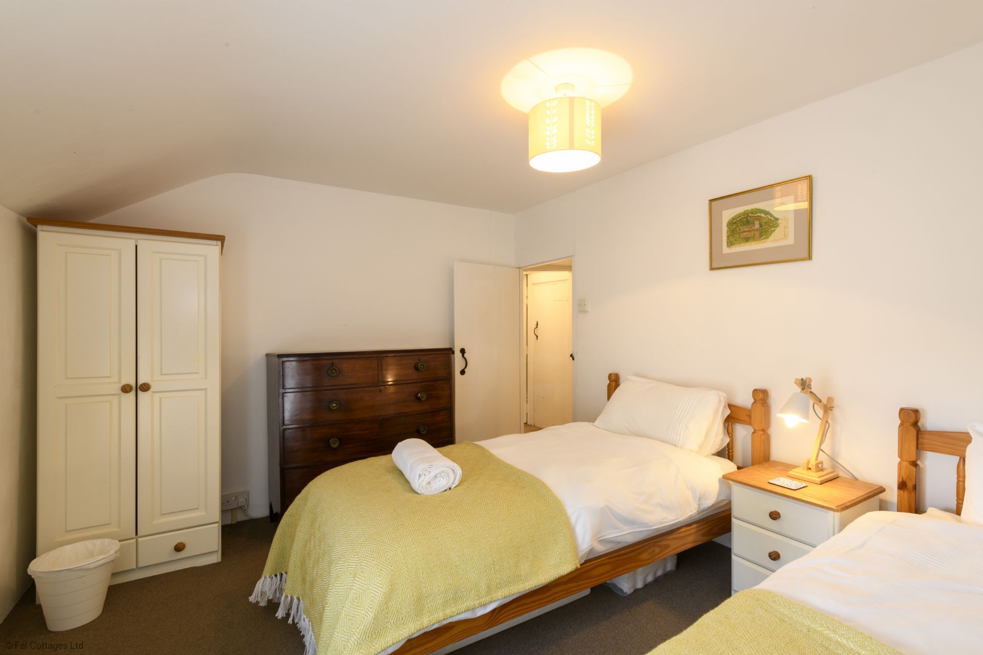Ein Schlafzimmer mit zwei Betten, einem hölzernen Schminktisch, einem weißen Kleiderschrank und einem gerahmten Bild an der Wand.