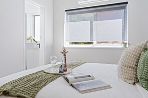A neatly made bed with a magazine, a glass of water, and a vase with flowers. - Cul-de-Sac Charm St Kilda (St Kilda)