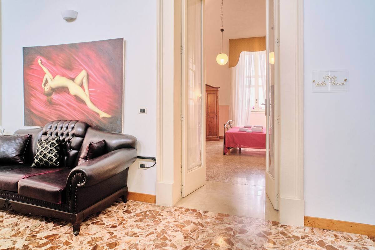 Una sala de estar con un sofá de cuero oscuro, un cuadro abstracto de gran tamaño y un suelo con diseño.