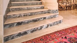 Una imponente escalera con peldaños de mármol, un candelabro y un cuadro en la pared.