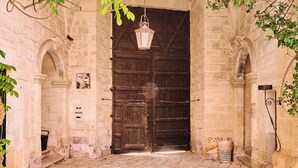 Una entrada de piedra arqueada con una puerta de madera oscura, un farol colgante y un camino adoquinado.
