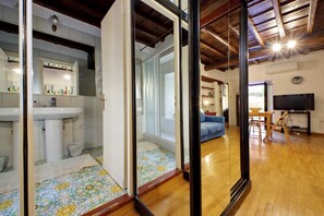 A modern interior with a bathroom, a living area with a sofa, and a TV.