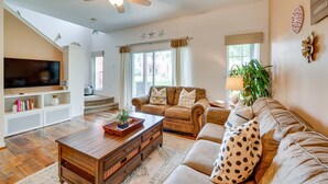 A spacious living room with a large flat-screen TV, a ceiling fan, and a staircase leading to an upper level. - 4 Mi to Disney: Emerald Island Resort Home! (Kissimmee)