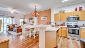 A modern kitchen with wooden cabinets, a central island, and stainless steel appliances. - 4 Mi to Disney: Emerald Island Resort Home! (Kissimmee)