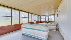 A covered outdoor seating area with two couches and a table, large windows, and a view of the outdoors. - 5 Mi to Golf: Charming Hernando Home w/ Deck (Hernando)