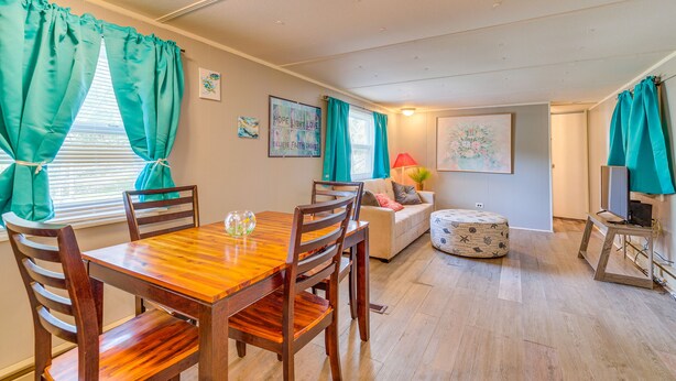 A dining area with a wooden table and chairs, a sofa, and a small ottoman. - 5 Mi to Golf: Charming Hernando Home w/ Deck (Hernando)
