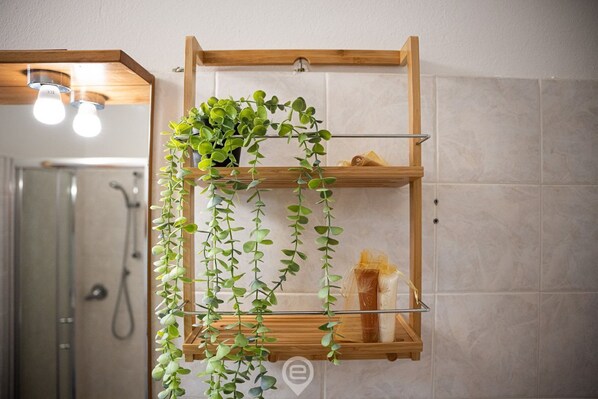 A bathroom with a wooden shelf holding a plant and a towel.