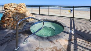 Un muro de piedra, una escalera de metal para la piscina y vistas a la playa.