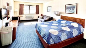 A hotel room with a large bed, a desk, a chair, a TV, and a bathroom. - One queen bed, private bathroom with jetted tub, mini fridge, and single-serve coffee maker. (Boulder Junction)