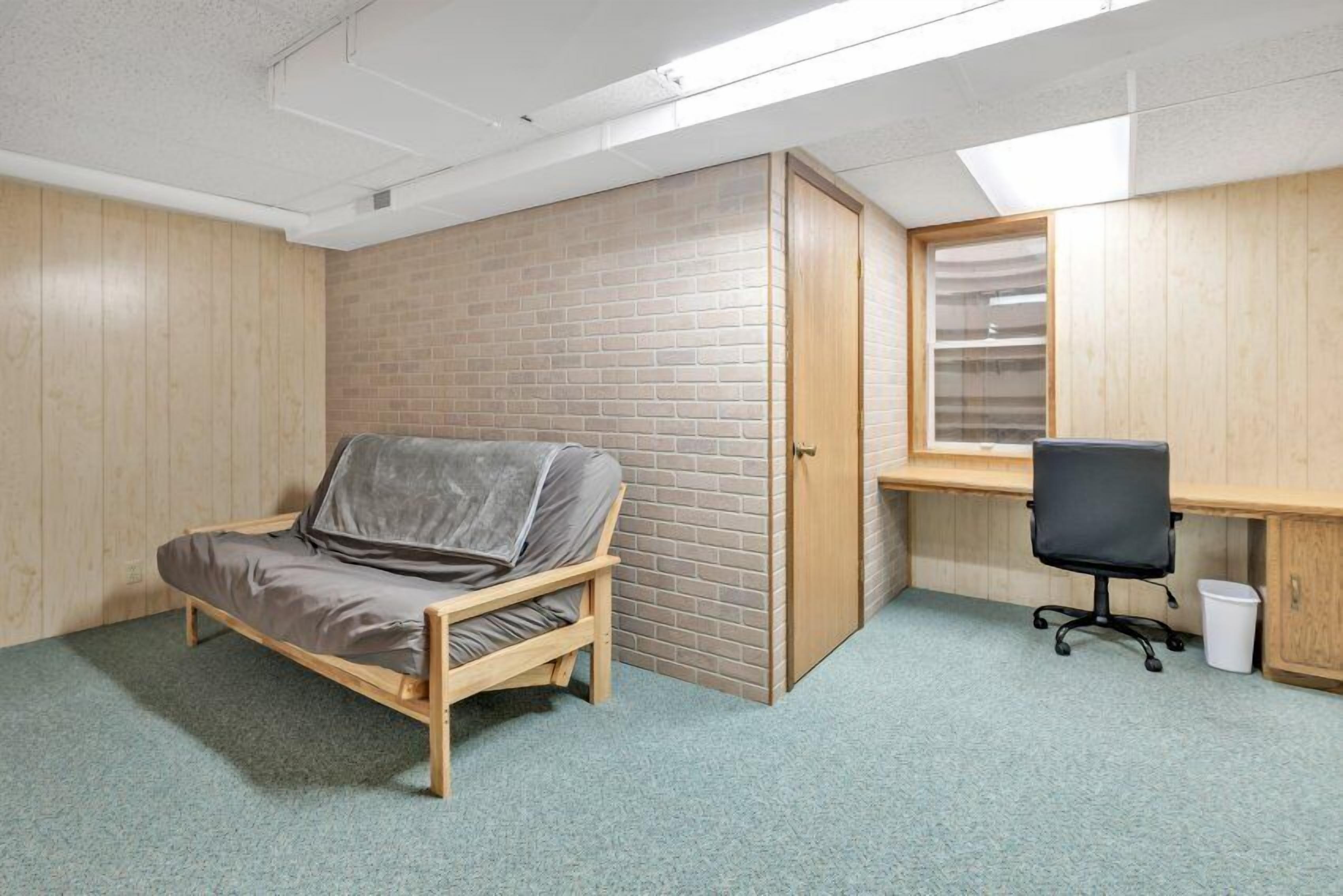 Une petite pièce avec un lit en bois, un bureau et une chaise.
