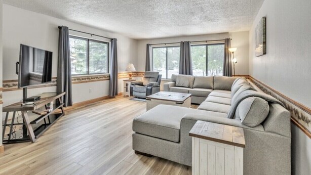 Un salón amplio con un sofá modular grande, un televisor de pantalla plana y una mesa de centro de madera.