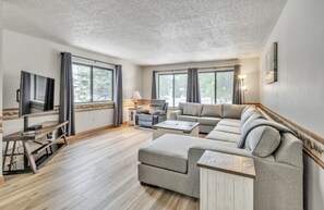 Un salón amplio con un sofá modular grande, un televisor de pantalla plana y una mesa de centro de madera.