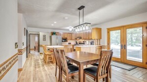Una cocina amplia con armarios de madera, una isla central y un comedor con una gran mesa y sillas de madera.