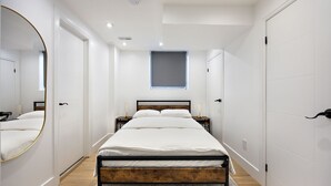 A modern bedroom with a bed, a large mirror, and a window. - Cozy & Charming Apt For 4 | Quiet & Privacy (Pickering)