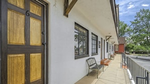 A building with a large wooden door, multiple windows, and a bench along the exterior wall. - Quest Rest - Unit 6 (Colorado Springs)