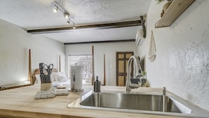 A kitchen with a stainless steel sink, wooden countertop, and a hanging light fixture. - Quest Rest - Unit 6 (Colorado Springs)