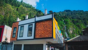 A modern building with a brick facade, large windows, and a visible chimney. - FABIS HOTEL (Baños de Agua Santa)