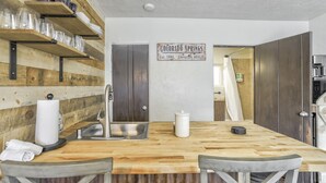 A kitchen with wooden shelves, a sink, and a sign indicating Colorado Springs.