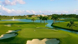 A golf course with sand bunkers, a water hazard, and a clubhouse in the background. - HOLIDAY RETREAT.★★★★★ 12. NEAR BEACHES / PGA / DOWNTOWN / ROGER DEAN STADIUM (Palm Beach Gardens)