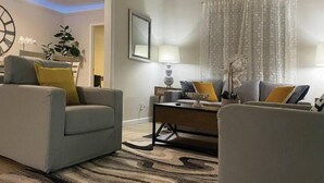 A modern living room with a sofa, armchairs, a coffee table, and a lamp. - HOLIDAY RETREAT.★★★★★ 12. NEAR BEACHES / PGA / DOWNTOWN / ROGER DEAN STADIUM (Palm Beach Gardens)