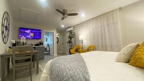 Ein Hotelzimmer mit einem großen Bett, einem Schreibtisch mit Stuhl, einem Fernseher und einem Deckenventilator.