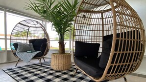 Una habitación con dos sillones colgantes de mimbre, una planta en maceta y una alfombra a cuadros.