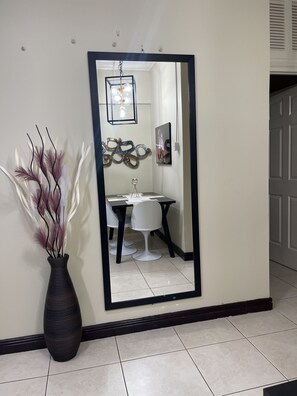 A spacious hallway with a dining area featuring a white table and two chairs, accompanied by a decorative vase.