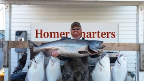 Une personne tenant un gros poisson, avec l’inscription « Homer charters » visible.