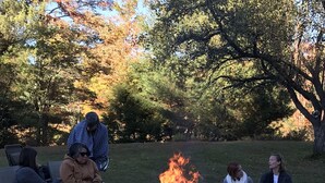 A group of people sitting on blankets around a campfire in a park. - Farmhouse on Otis Pond (Otis)