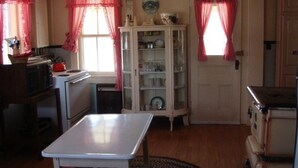 A kitchen with a table, cabinets, and a stove. - Farmhouse on Otis Pond (Otis)