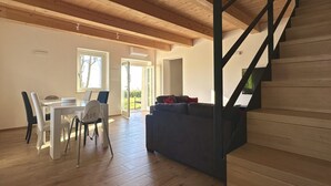 Une pièce spacieuse comprenant un coin repas, un canapé et un escalier.