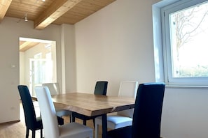Un comedor con una mesa y sillas de madera, una ventana con vistas y un techo de madera.