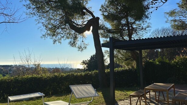 Une terrasse agrémentée d’une pergola, d’une table et de chaises, offrant une vue sur un paysage pittoresque.