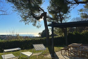 Een terras met een pergola, een tafel en stoelen, met uitzicht op een mooi landschap.