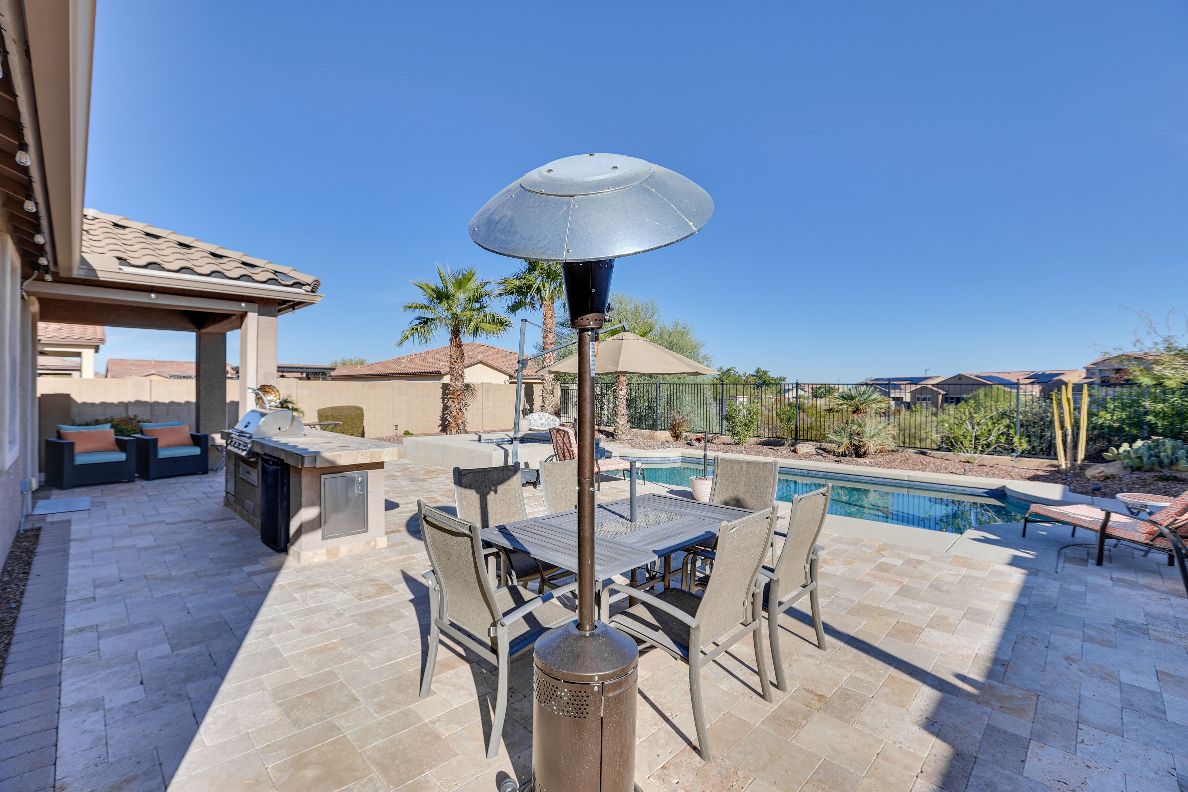 Une terrasse extérieure équipée d’un barbecue, d’une table à manger et de chaises, ainsi que d’une piscine et d’une pergola.