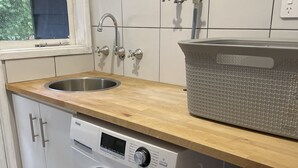 Zona de bugaderia reduïda amb rentadora, dues rentas i un tendal.