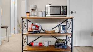 A kitchen area with a coffee maker, microwave, toaster, and various kitchen items on a wooden shelf. - Family Friendly with Kid activities (Tifton)