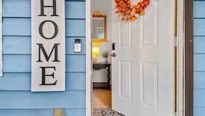 A home entrance with a 'Welcome to our HOME' sign, a door with a wreath, and a visible interior including a lamp and a small table. - Family Friendly with Kid activities (Tifton)