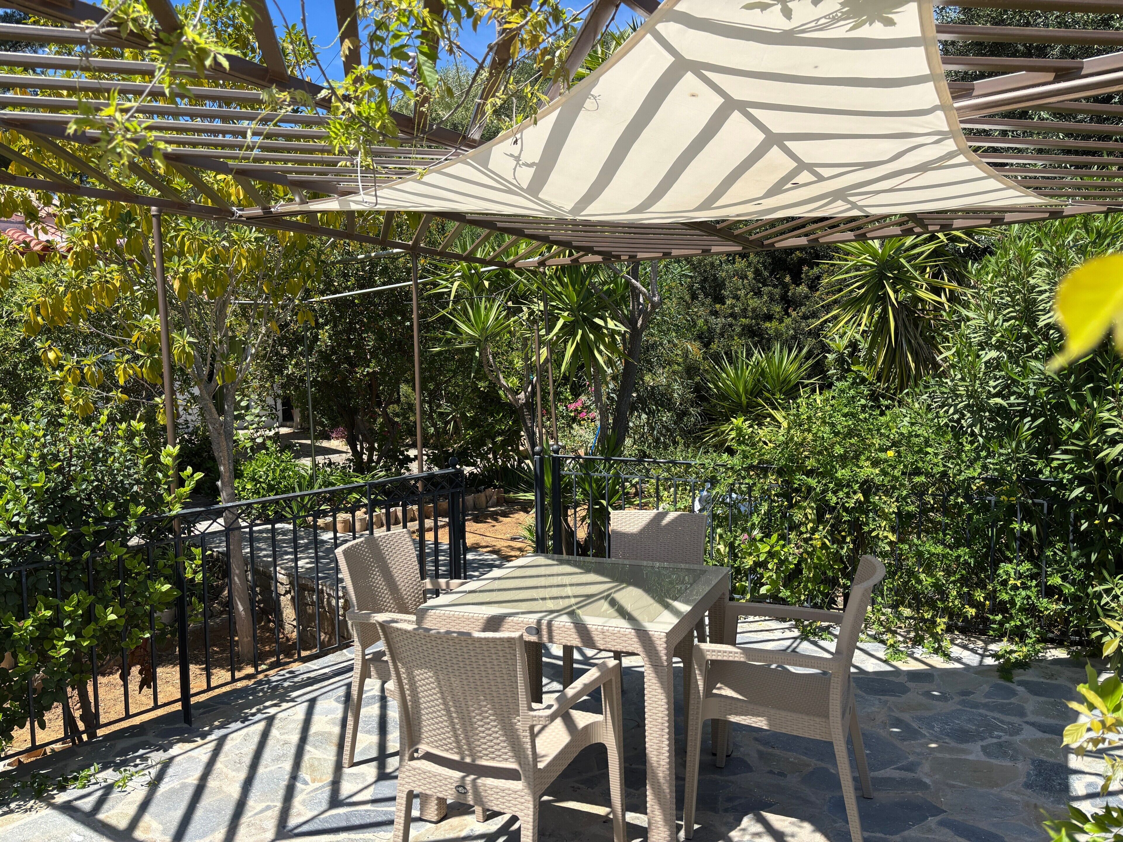 Eine Außenpatio mit Korbmöbeln, einem Pergola mit Dach und einem Steinboden.