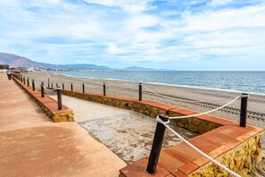 Une promenade en bord de mer agrémentée d’un muret en pierre, de poteaux en bois et d’une barrière en corde.