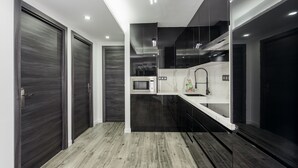 Cocina moderna con armarios oscuros, un microondas y un lavamanos.