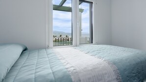 Un dormitorio con cama, ventana con vistas y balcón.