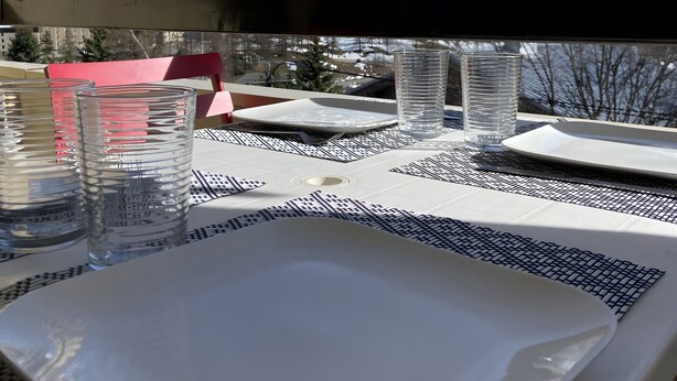 A dining table with a white plate, two clear glasses, and a water bottle.