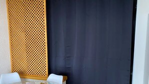 A room with a round glass table, white chairs, a dark curtain, and a wooden partition.