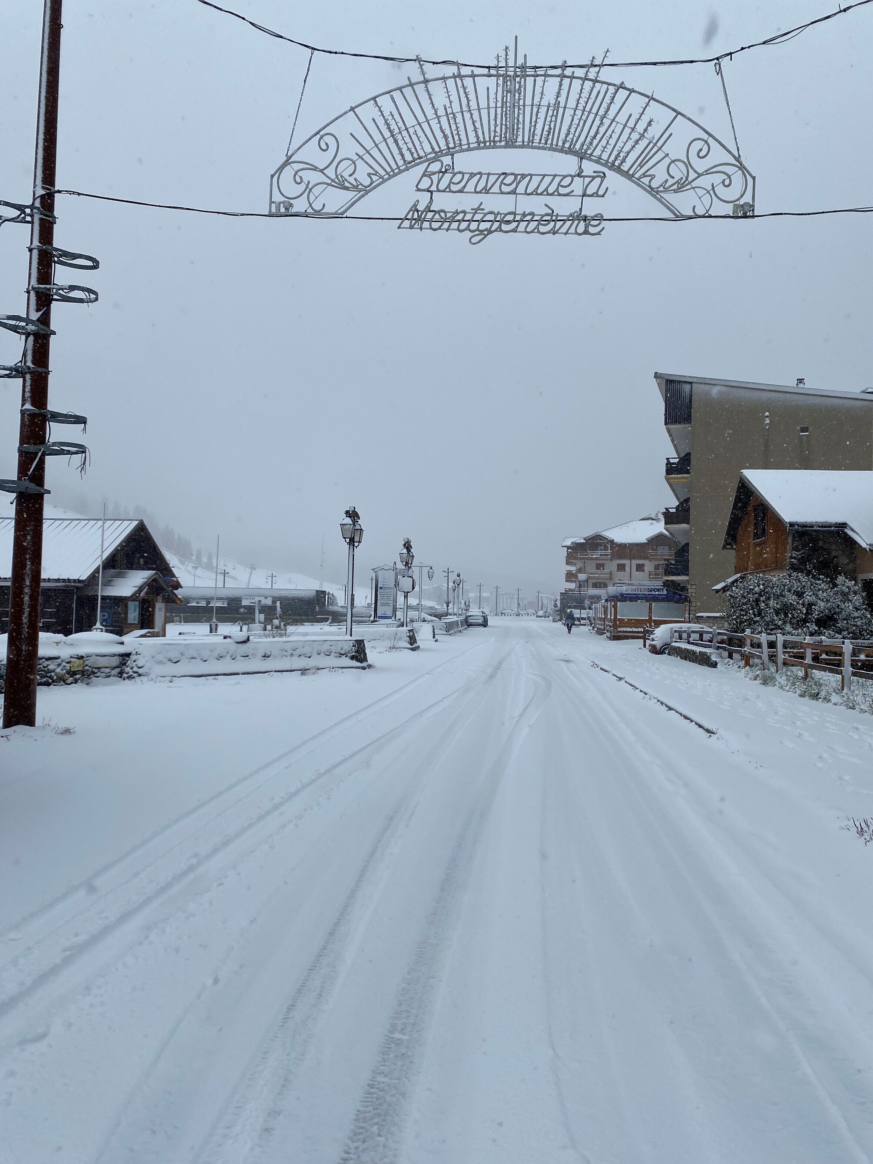 Uma estrada coberta de neve com uma placa indicando 'Bienvenue Montgenest'.