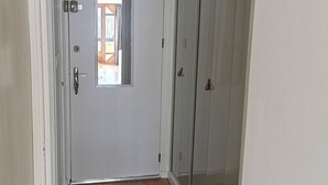A narrow hallway with a white door, a small window, and a sliding glass door leading to a room.