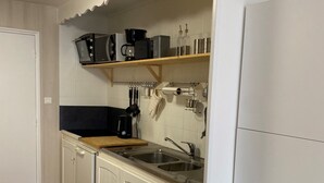 A compact kitchen with white cabinetry, a wooden countertop, a double sink, and a built-in oven.